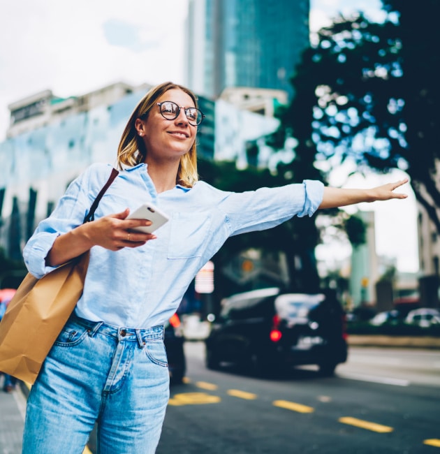 Smiling female traveler in trendy casual wear raising hand calli